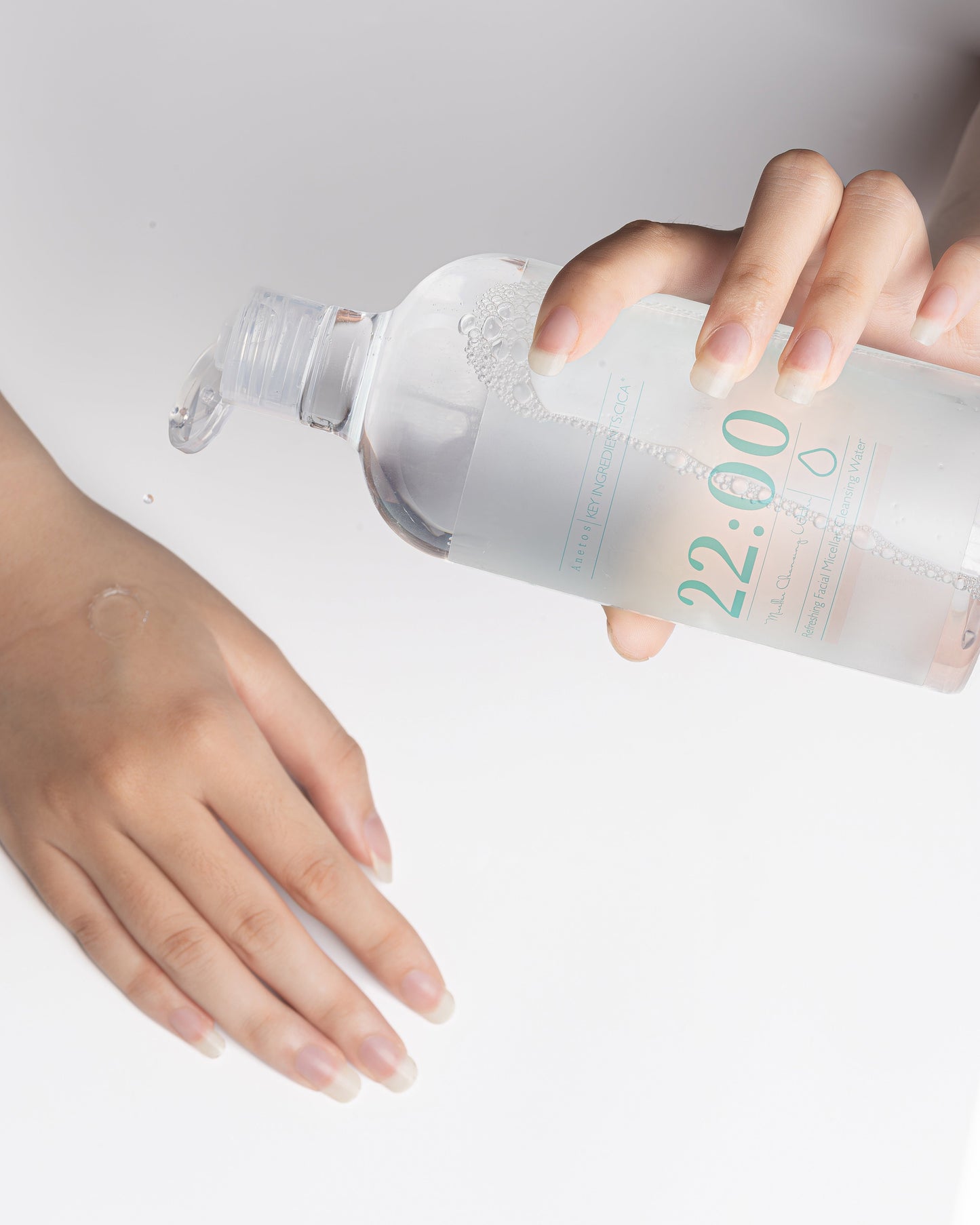 アネトス フェイシャル クレンジング ウォーターを手に持つ女性の手、清潔感のあるデザインのボトル